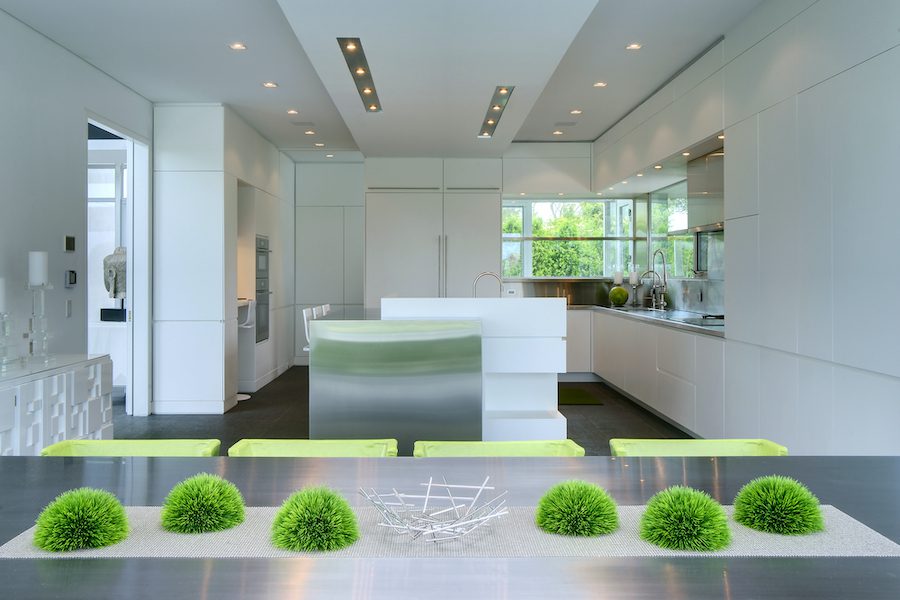 A white kitchen with green plants on the table.