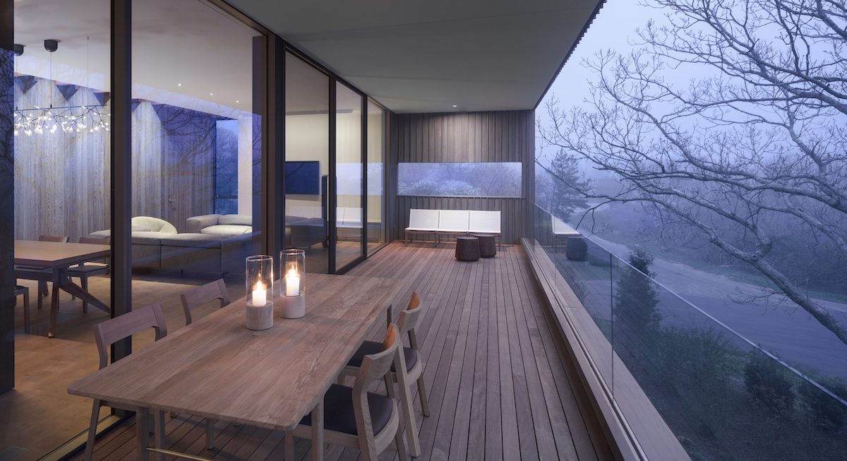 A balcony with a table and chairs overlooking a wooded area.