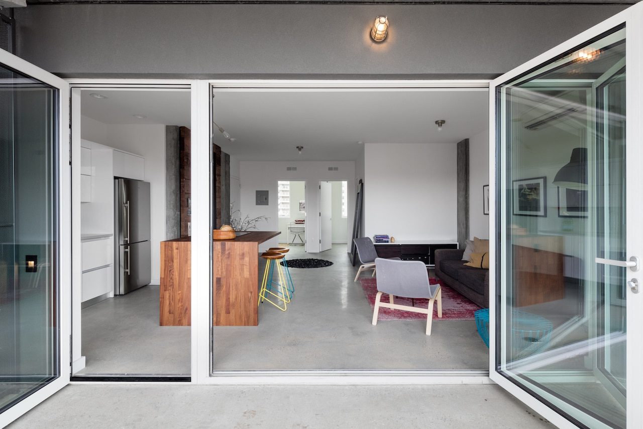 A glass door opens up to a living room and kitchen.