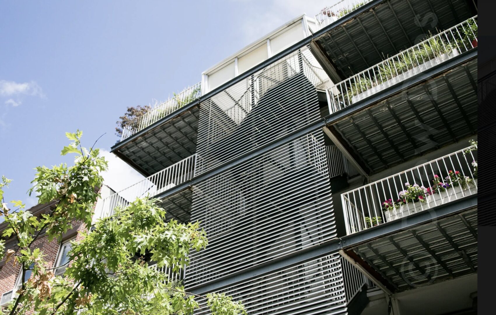 An apartment building with balconies and plants.