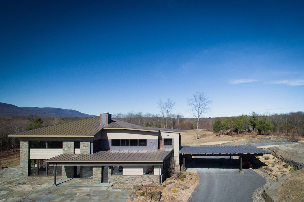 A modern home with a large driveway and a mountain view.