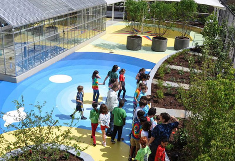 A group of children are standing around a colorful playground.