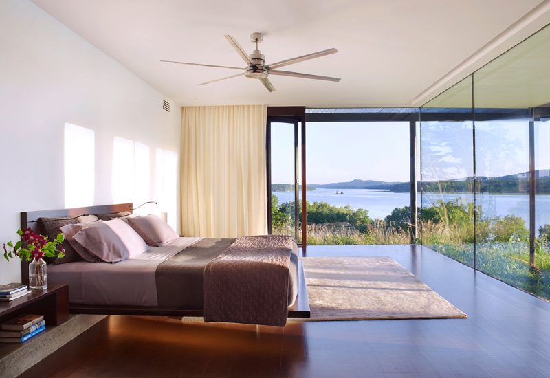 A bed in a room with a view of a lake.