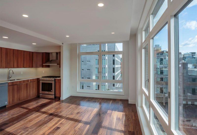 An empty kitchen with hardwood floors and a view of the city.