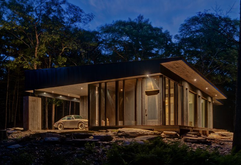 A modern house in the woods at night.