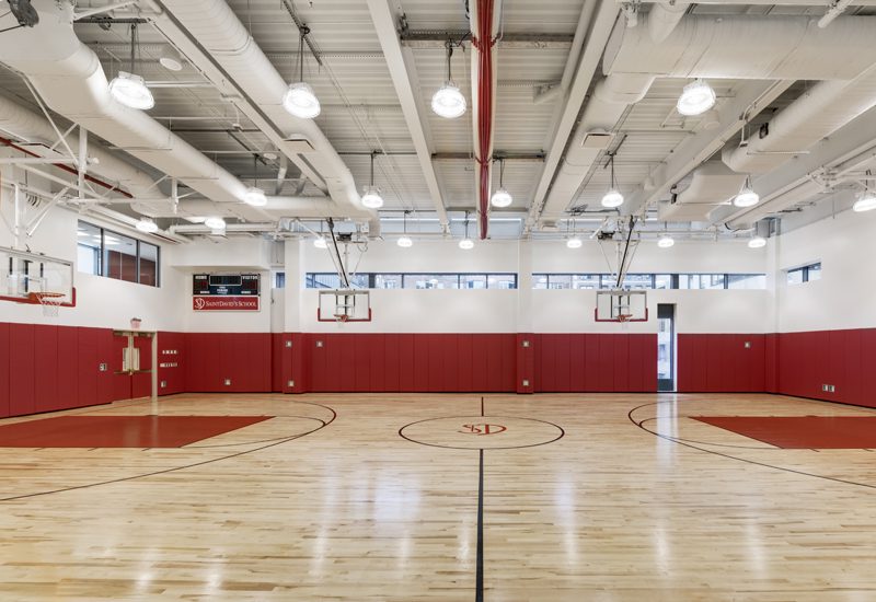 An empty basketball court with red walls and lights.