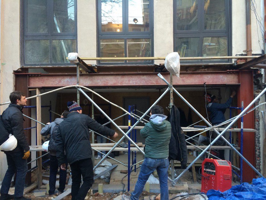 A group of people standing in front of a building with scaffolding.