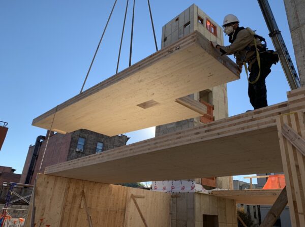 A man is working on a wooden beam in a construction site.