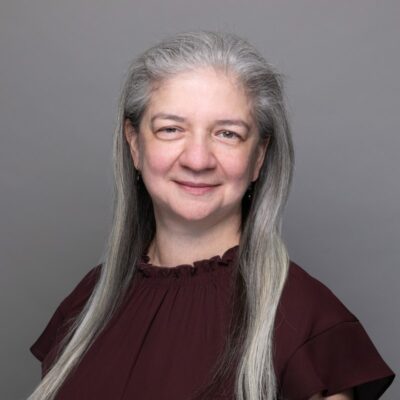 A woman with gray hair and a maroon top.