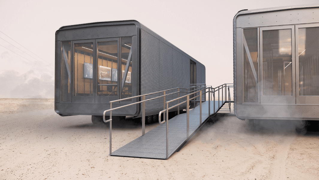 Two small houses in the desert with a walkway.