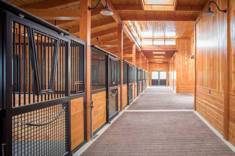 A long hallway with wooden stalls in a horse barn.