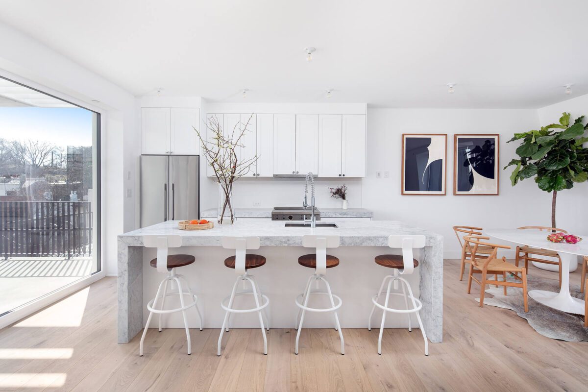 A white kitchen with wooden floors and stools.