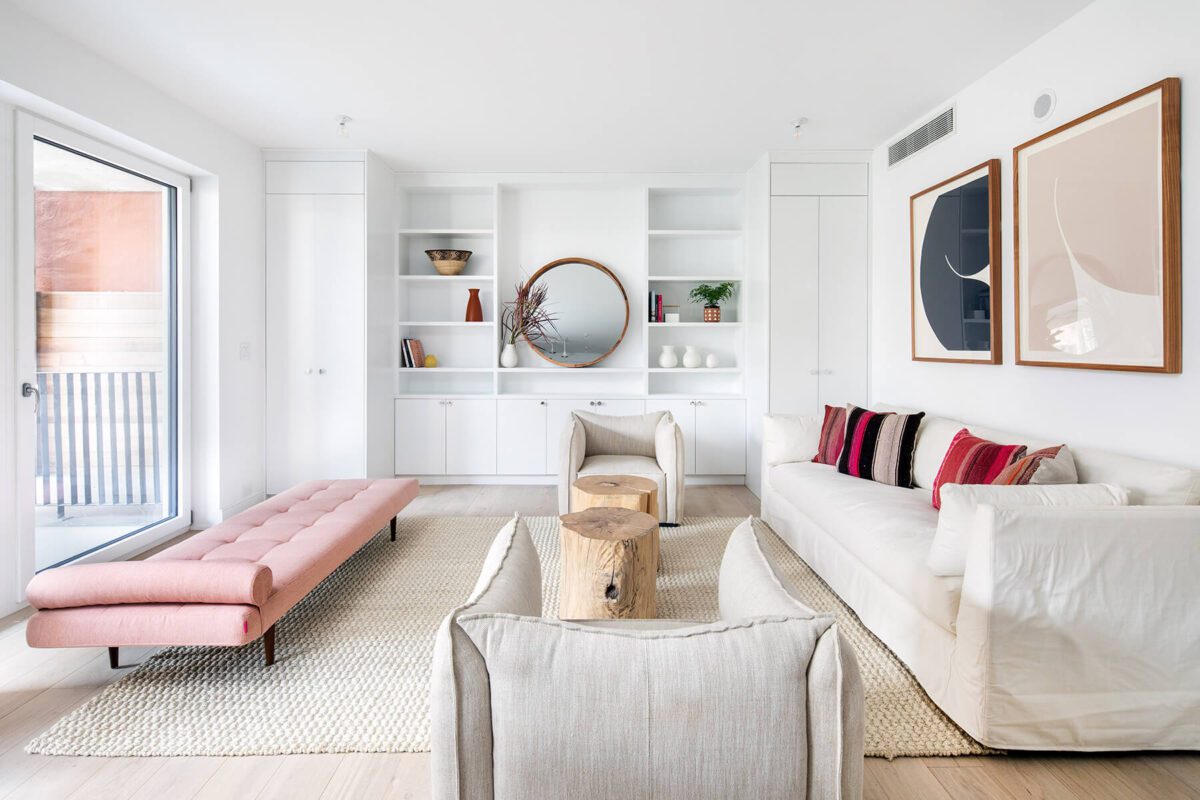 A living room with white furniture and pink accents.