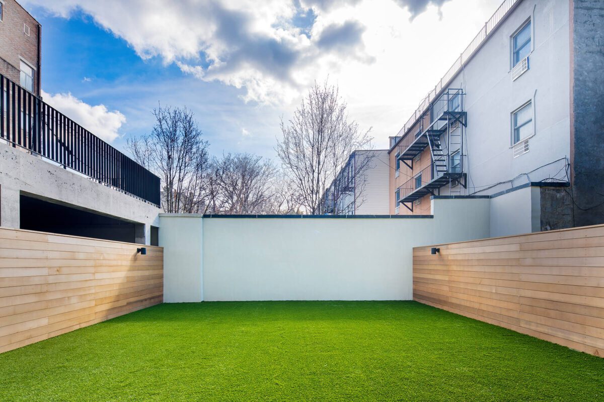A backyard with artificial grass and a wooden fence.