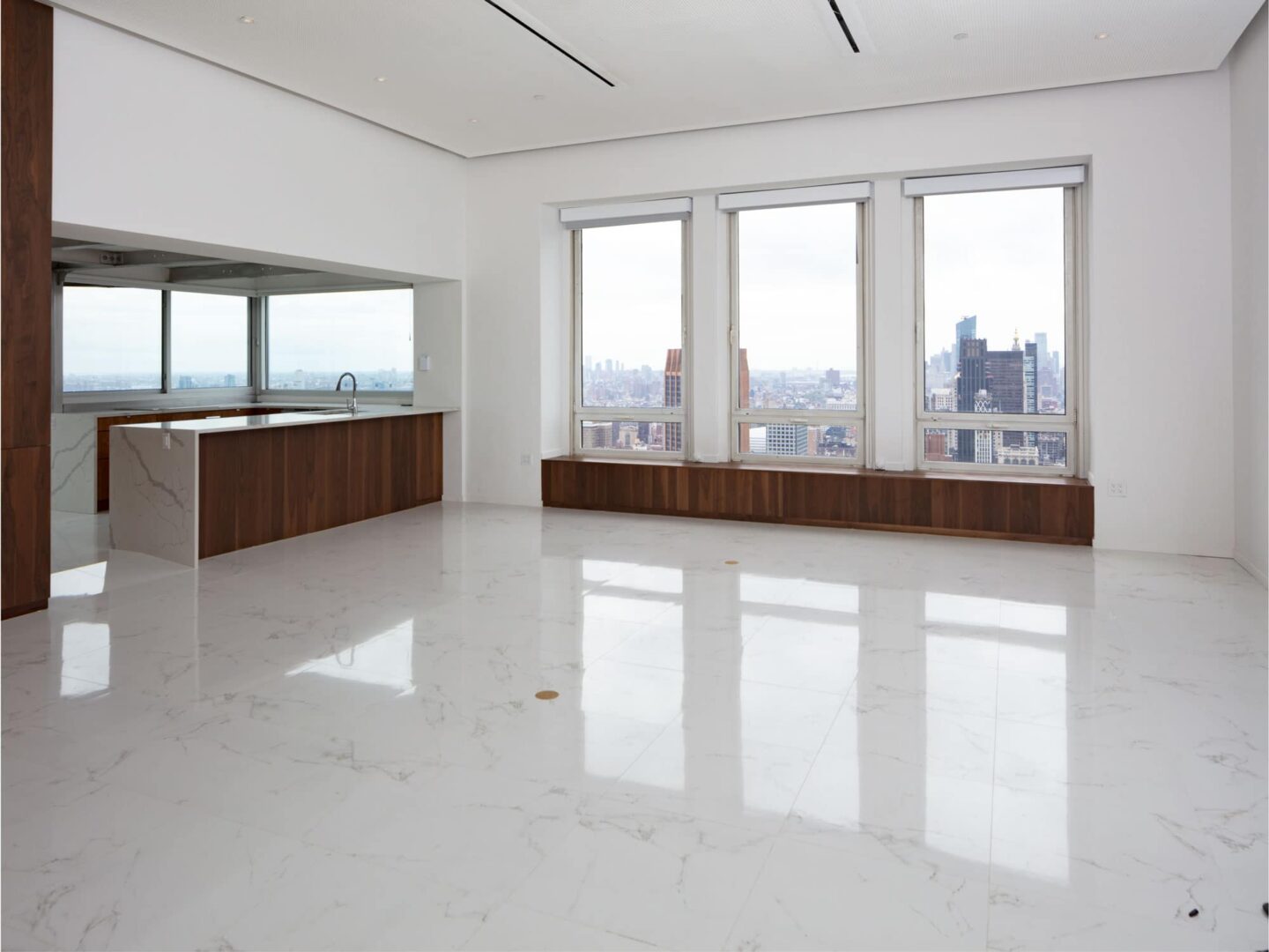 An empty room with marble floors and a view of the city.