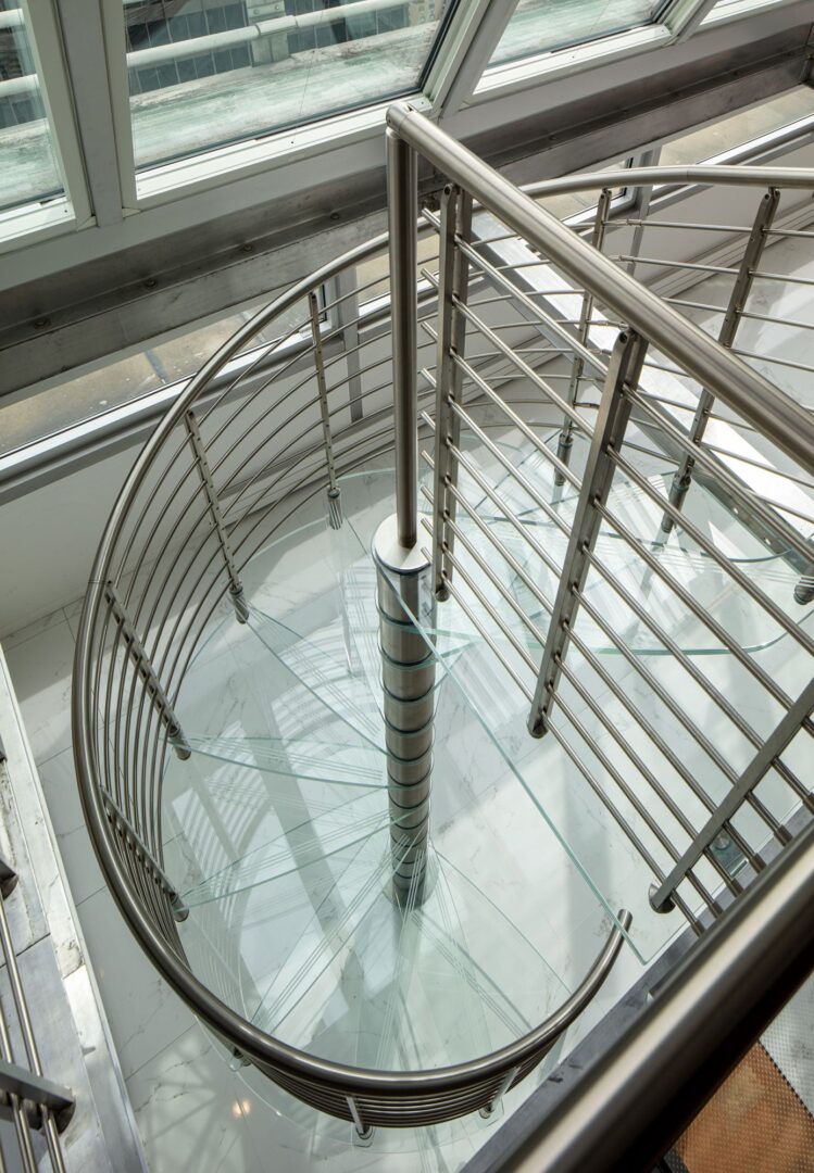 A spiral staircase in a building with glass railings.