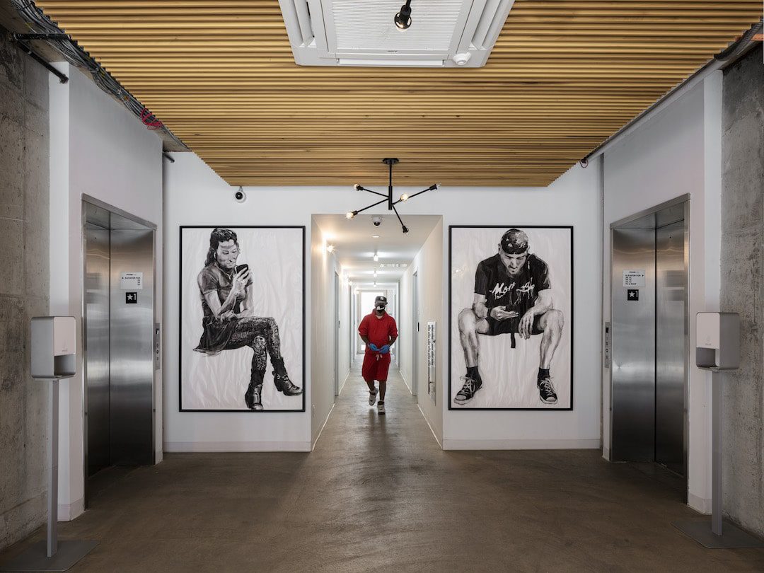 In the first Cross Laminated Timber building in New York City, a man in a red jacket walks down the hallway, heading towards the elevator.