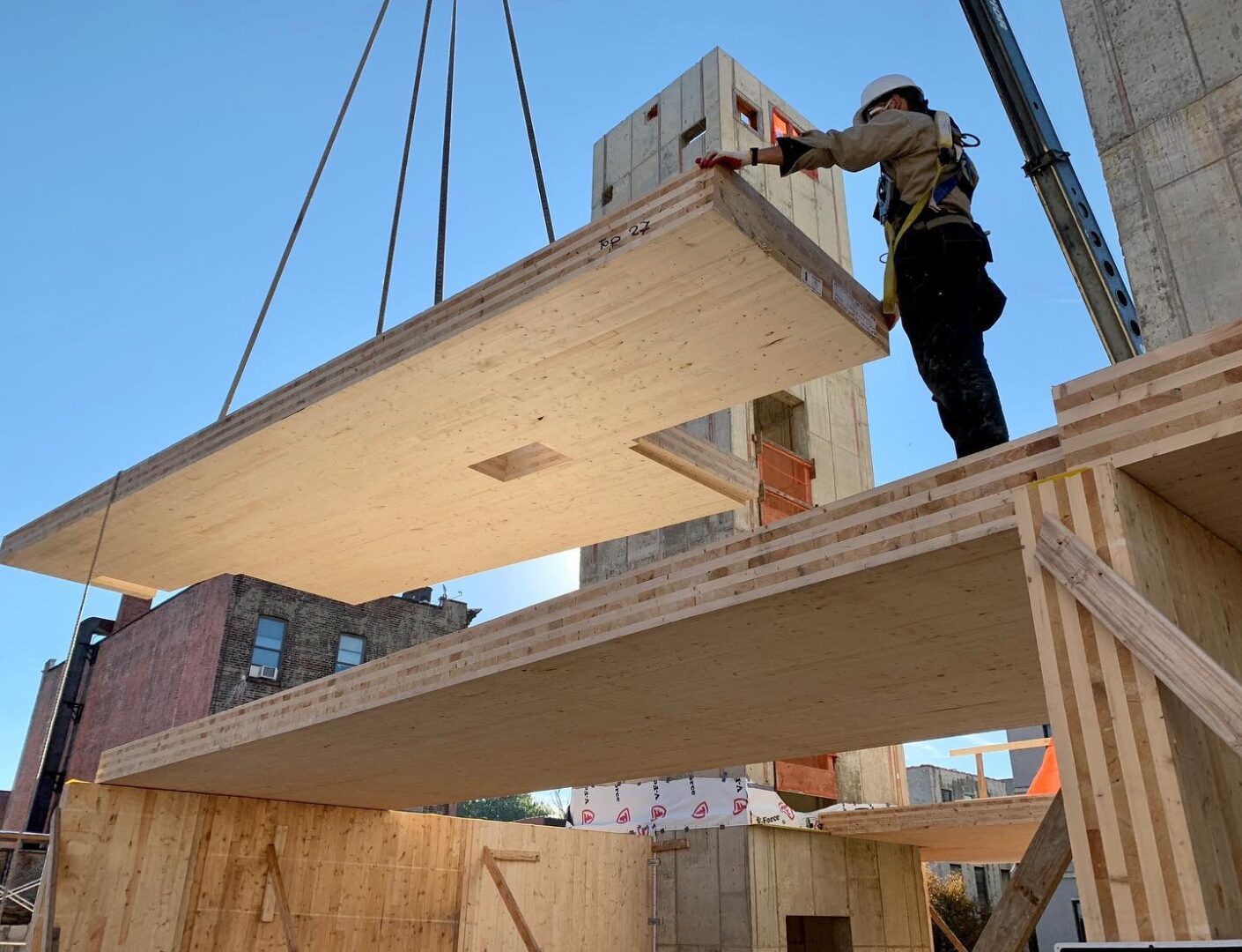 A man is working on a construction site with wooden beams, building the First Cross Laminated Timber building in New York City.