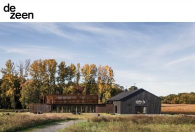 A black barn in the middle of a field exudes a sense of rustic hospitality.
