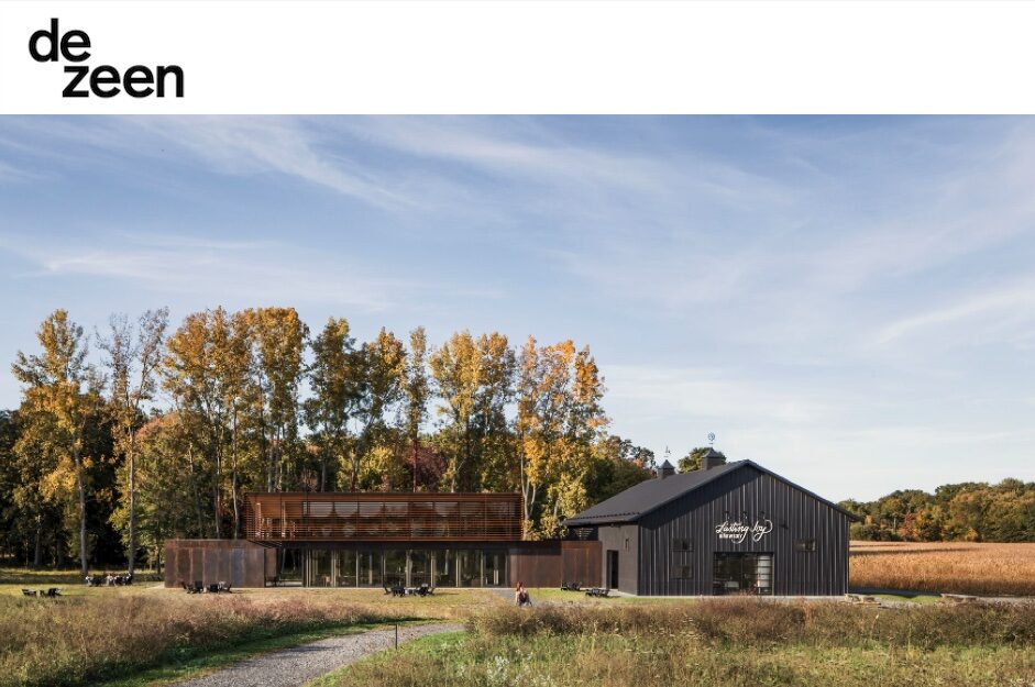 A black barn in the middle of a field exudes a sense of rustic hospitality.