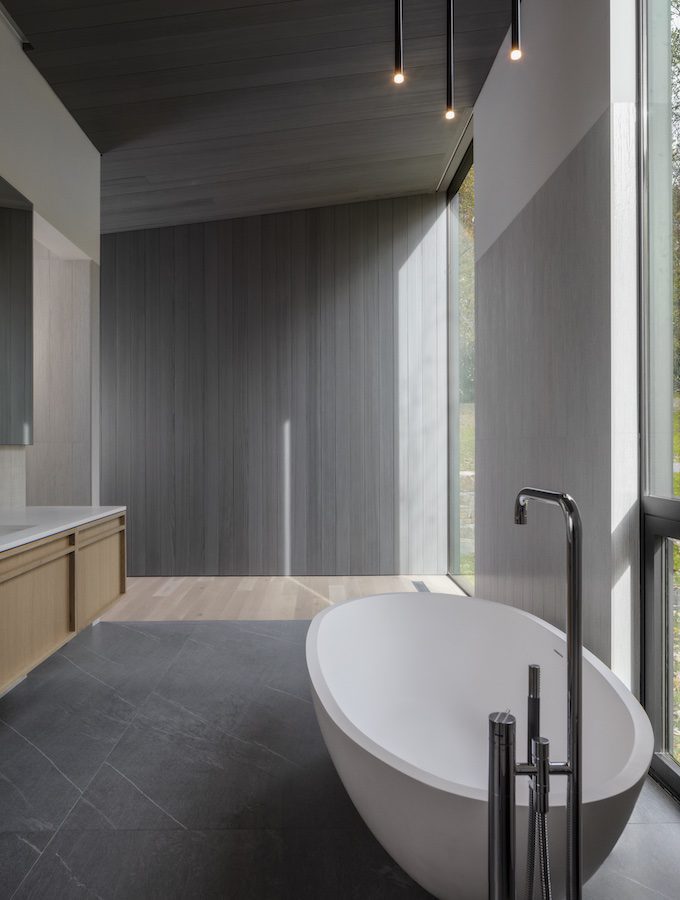 A modern bathroom with a large tub and large windows.