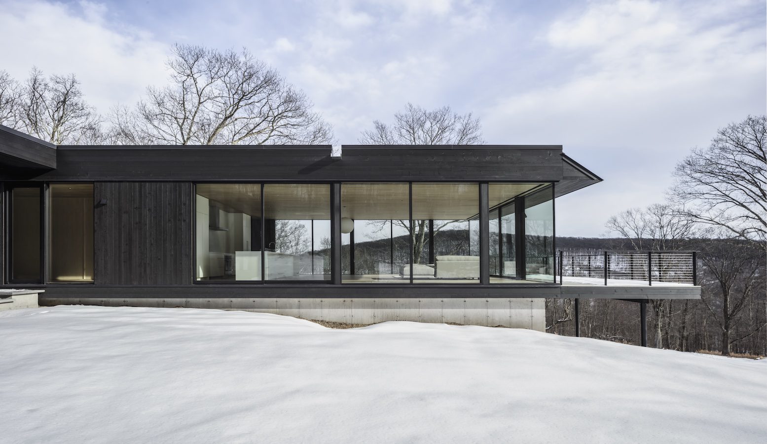 Residential: A modern black house sits on a snowy hillside, showcasing exemplary residential structural design.
