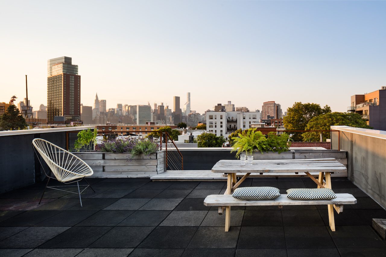 A table and chairs on a rooftop with a view of the city.